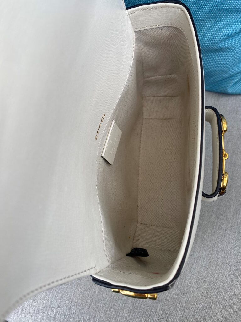 The interior of a small white leather bag